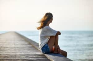sad woman sitting alone on pier